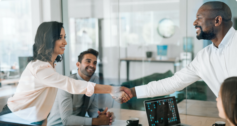 A woman and a man both smiling shaking hands