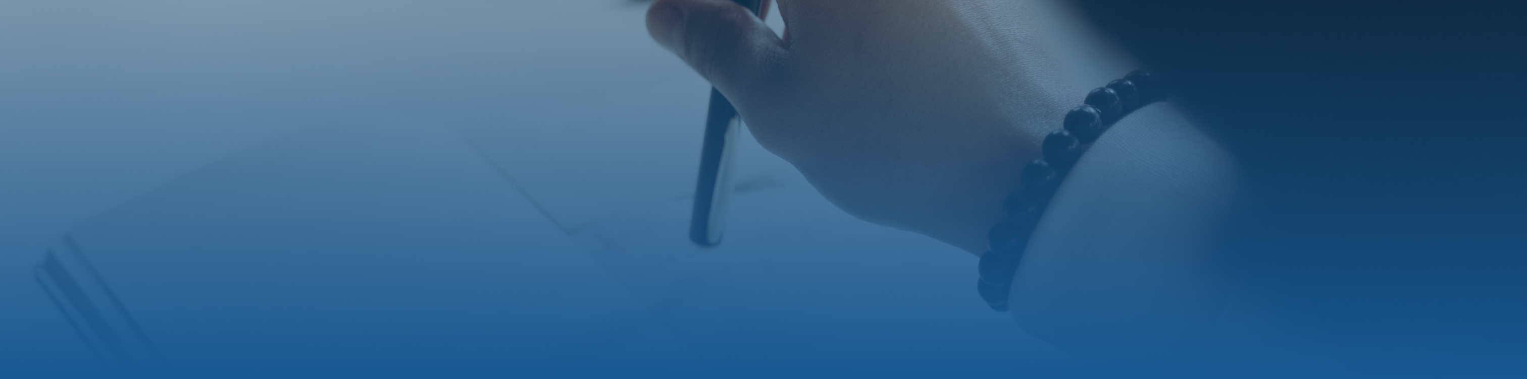 Blue tint frame hero image with a closeup of a persons hand holding a pen over a notebook