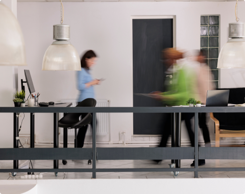 Well lit office space with 3 individuals in a blurred motion 
