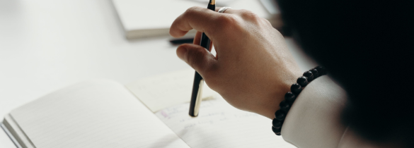 closeup of a persons hand holding a pen over a notebook